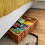 Caisse ajourée terracotta sous un lit, contenant des livres.